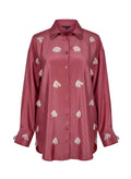 Pink shirt with white floral patterns on a white background